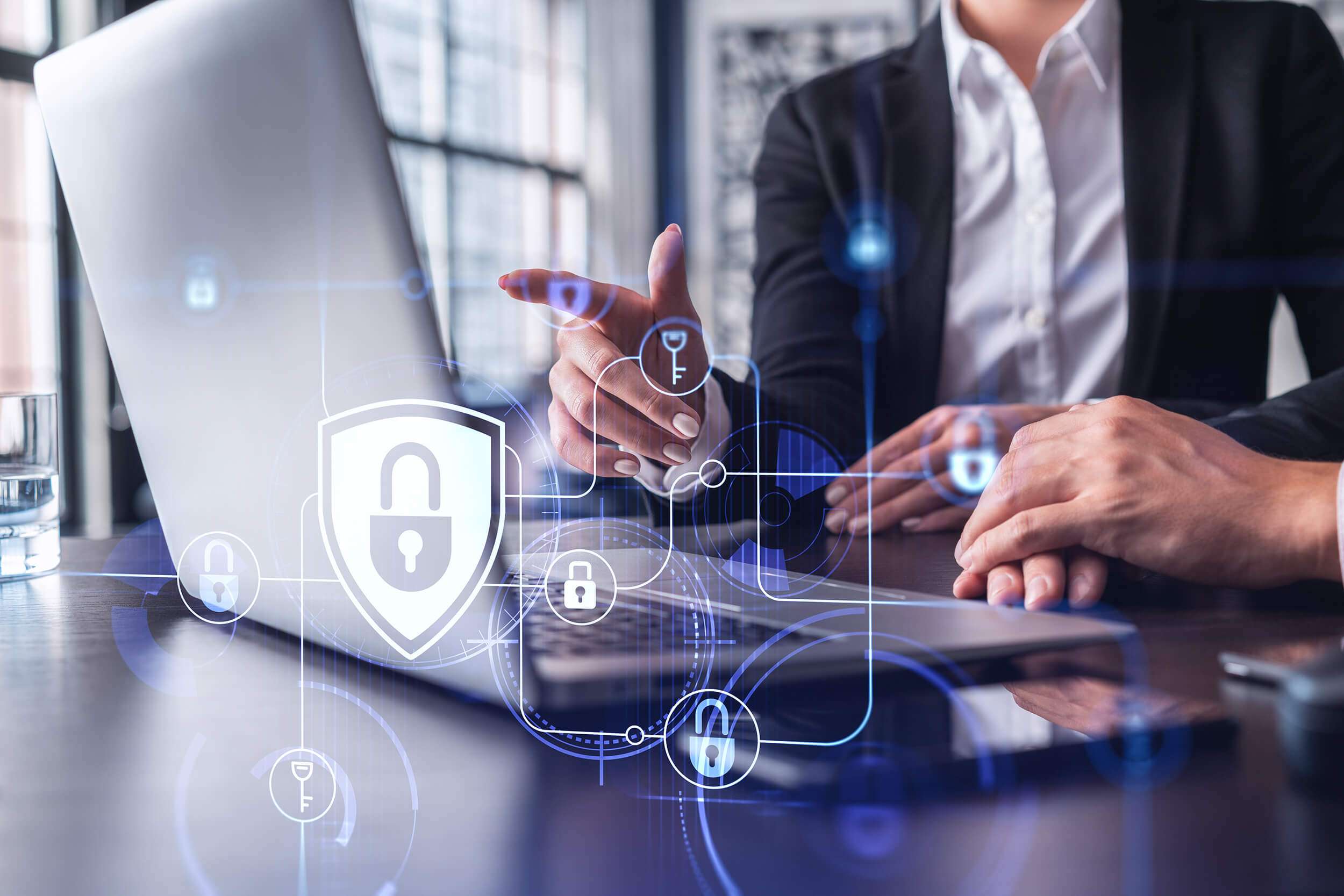 Two people sitting in front of laptop with illustration of lock and safety symbol